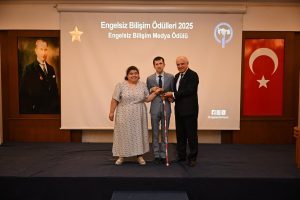 Ödül törenine ait fotoğraafta, ortada takım elbise giymiş ve elimde beyaz baston tutar halde ben varım. Sağımda takım elbiseli Gökmen Dağlı, solumda desenli açık renkte elbise giymiş halde olan eşim Ayşegül var. Üçümüz birlikte el ele tutuşuyoruz ve elimizde  plaket var.  Arkamızda “Engelsiz Bilişim Ödülleri 2025 - Engelsiz Bilişim Medya Ödülü” yazılı bir projeksiyon perdesi var. Sol köşede Atatürk'ün portresi, sağ köşede ise Türk bayrağı asılı. Sahnenin sağ alt köşesinde sosyal medya ikonları ve @engelsizbilisim hesabı yazılı. Betimleme: Be My Eyes yapay zeka