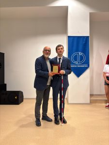 Fakülte Dekanı ile birlikte sahnede elimizde kırmızı kadife kutu içerisinde yer alan altın sarısı renkte bir plaket tutuyoruz.